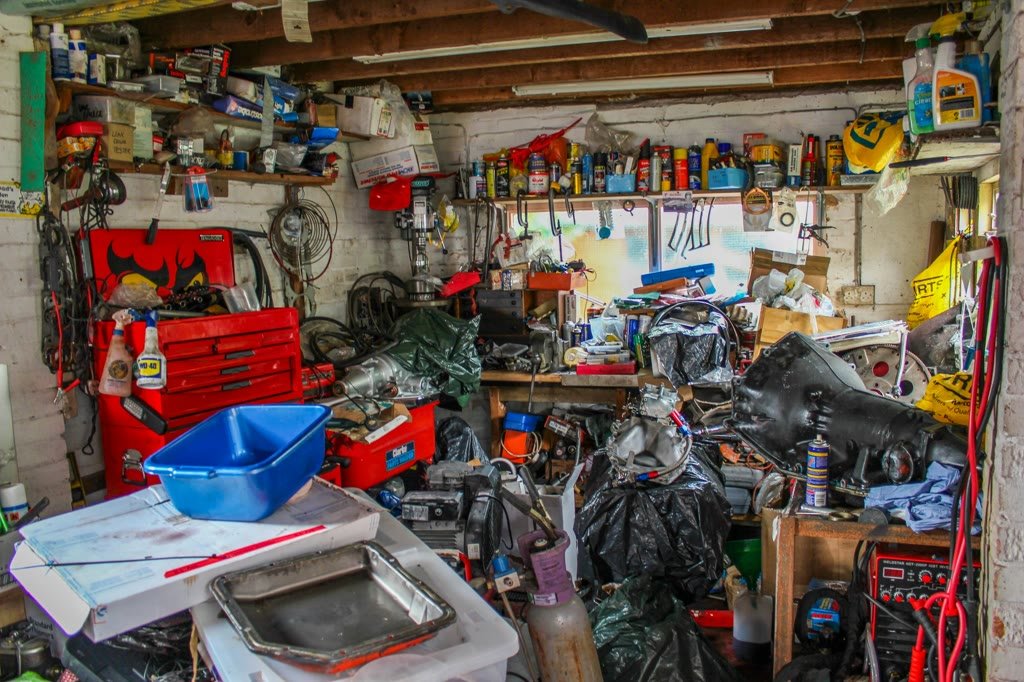 A one-car garage packed to the door with boxes, tools, and old furniture