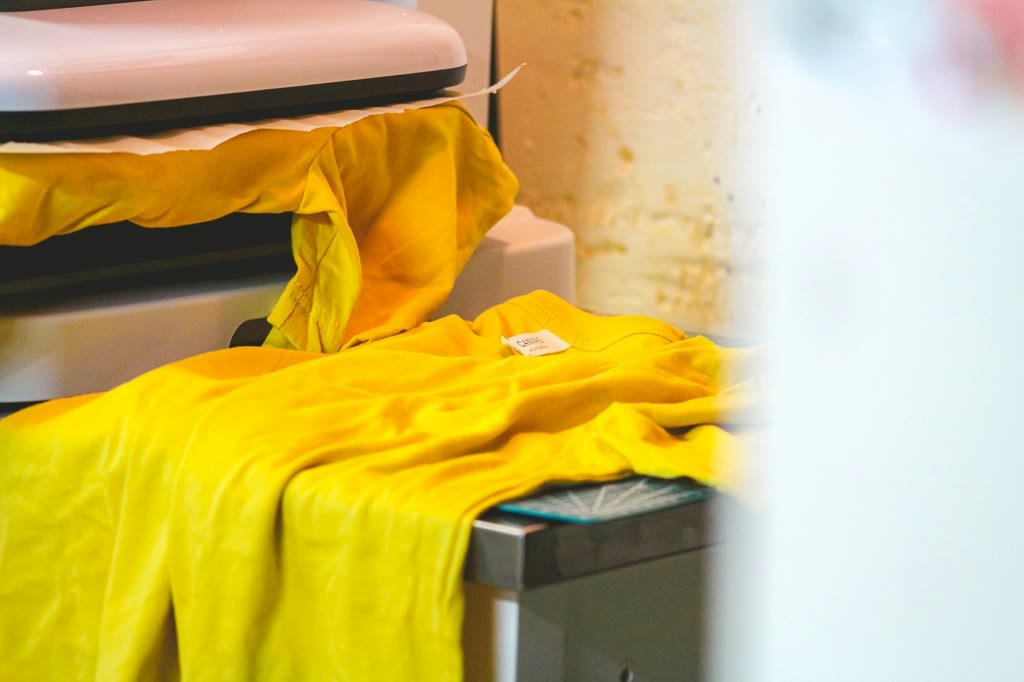 Yellow shirts laid out at a commercial heat press