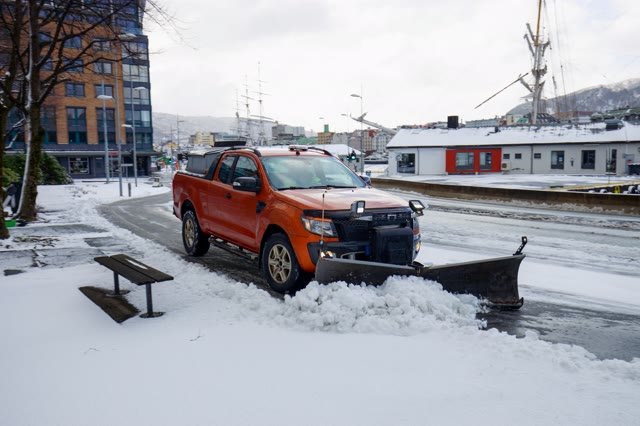 A pickup truck with a plow blade on a snowy road