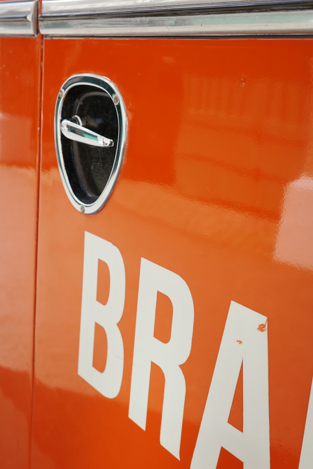 White vinyl lettering on the door of an orange work truck