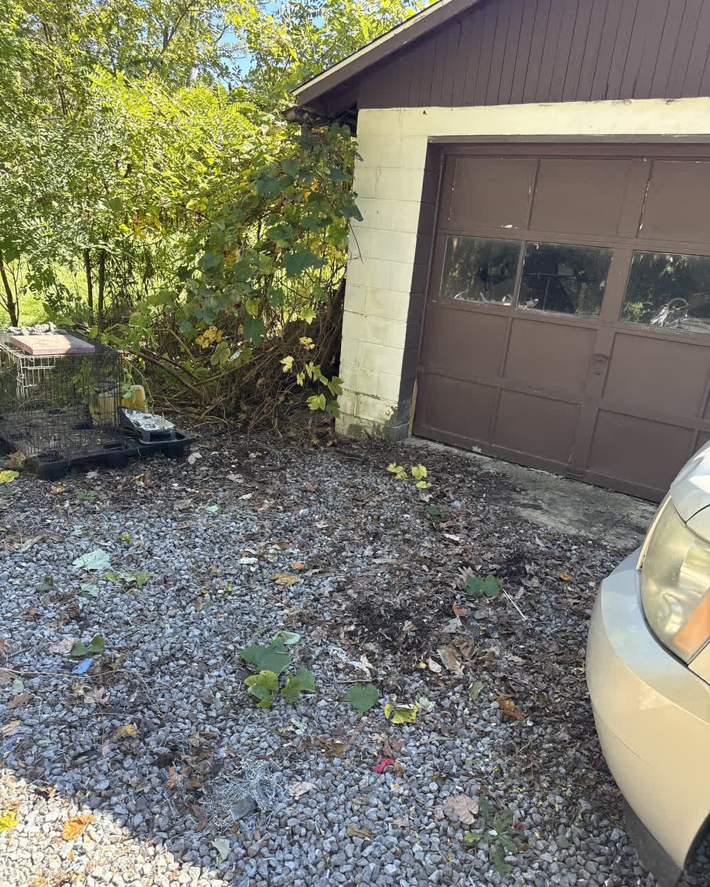 The same gravel pad beside the garage door, cleared, with the pile gone